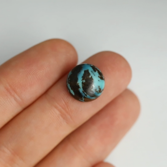 Turquoise stone on a person's finger against a white background